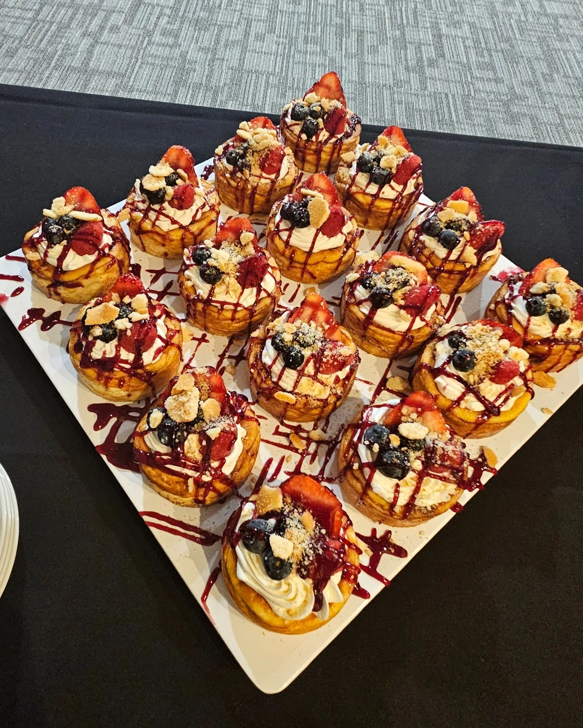 Individual berry-topped desserts prepared for an event